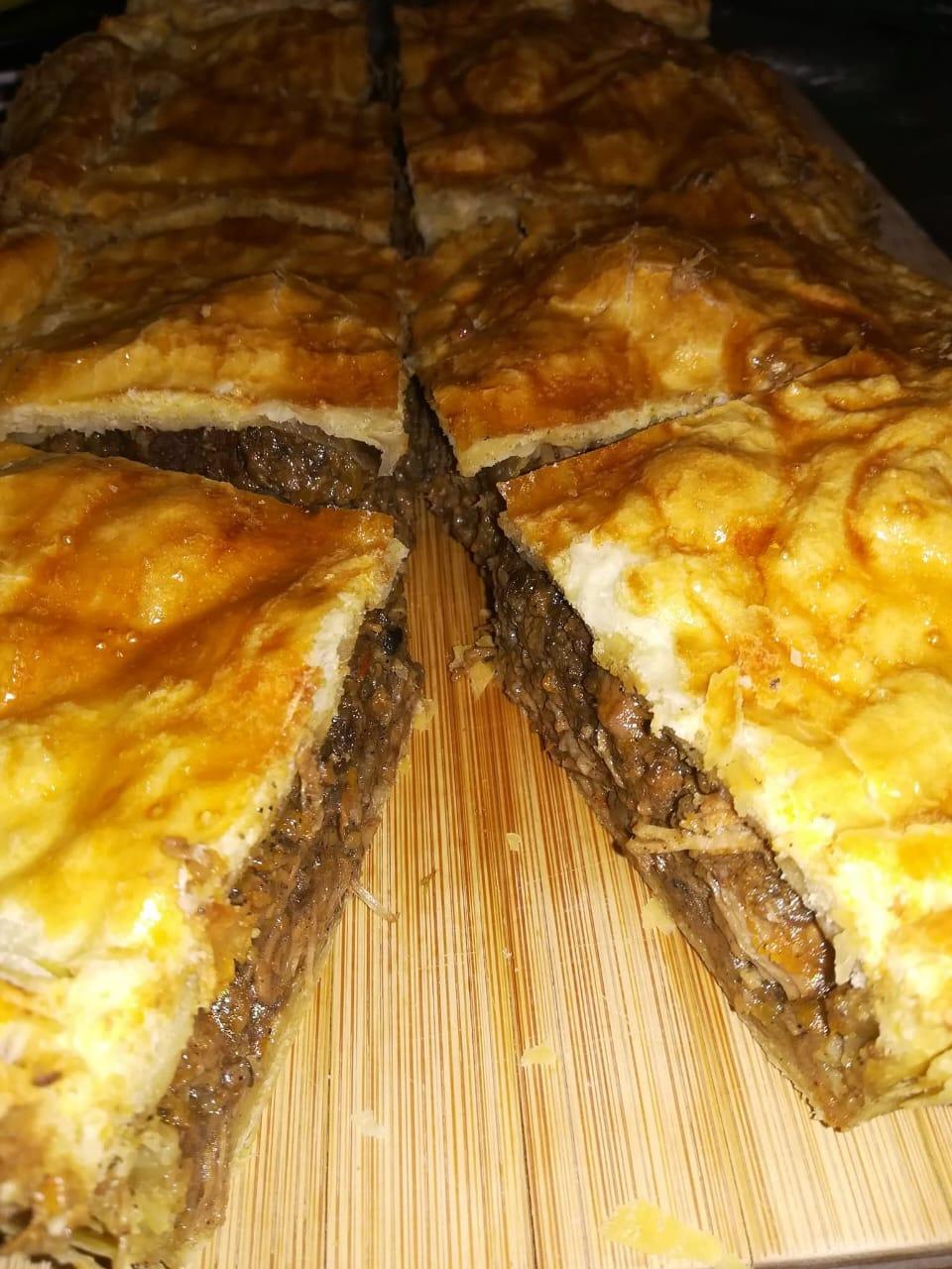 Freshly baked beef pie, sliced on a wooden board